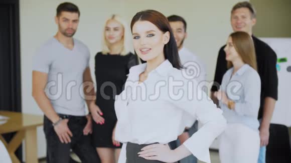 一个英俊的女人和一群年轻的商人在后台视频的预览图