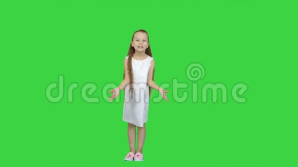 年轻的女士穿着可爱的衣服穿着白色的鞋子在绿色的屏幕上唱着一首歌ChromaKey视频的预览图