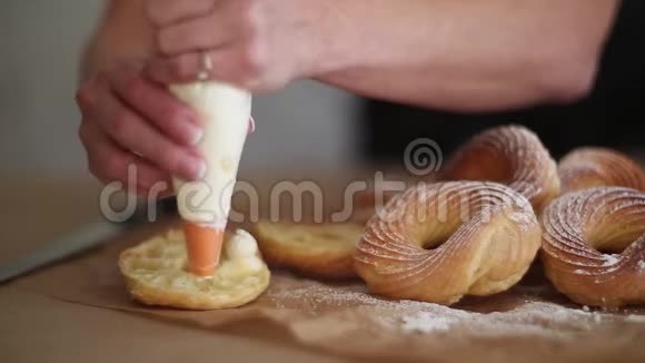 女人她的手是用奶油冻或干酪在烤纸上煮成的自制油饼视频的预览图