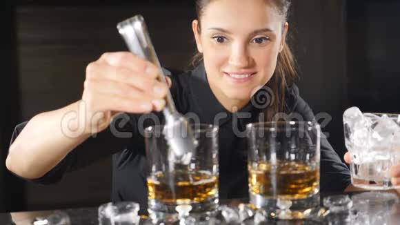 女酒保服务员准备酒精鸡尾酒缓慢地滴下冰块友好微笑服务视频的预览图