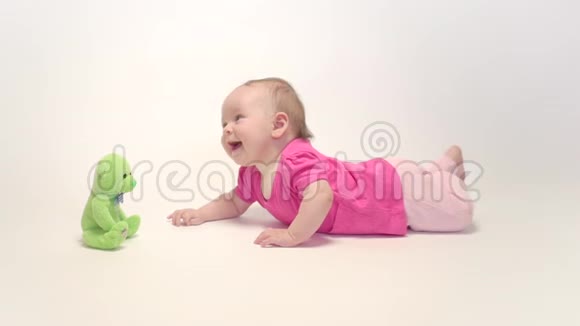 可爱的女婴在白色背景下学习爬行和玩五颜六色的玩具视频的预览图