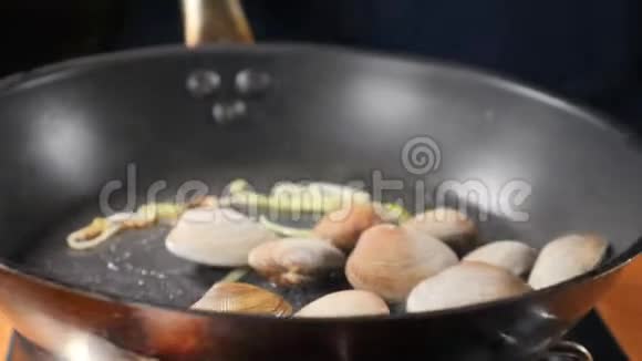 厨师手把贻贝用贝壳翻炒混合和在平底锅上投掷海鲜被煮熟视频的预览图
