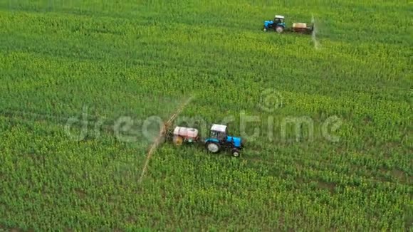 两台拖拉机相互驾驶的空中视野并在油菜地上的农业植物上喷洒肥料视频的预览图
