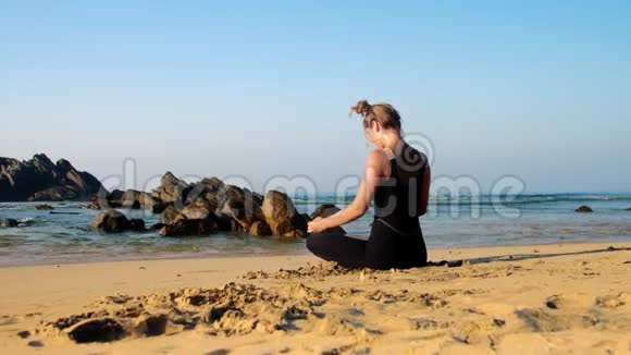 女孩伸展颈部和背部的瑜伽姿势蓝色海洋视频的预览图