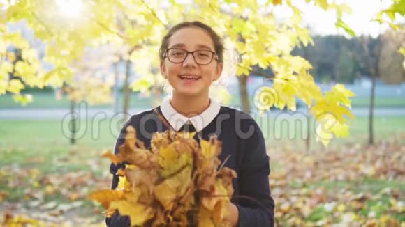 快乐的少女在秋天公园扔树叶视频的预览图