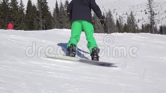 滑雪坡上穿绿黑色西装的滑雪者慢动作视频的预览图