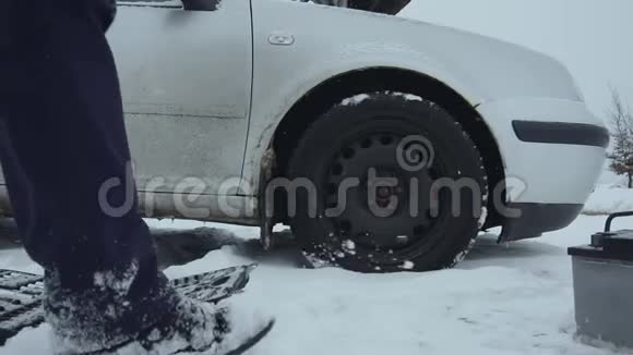 人类在冬天从积雪覆盖的地面上举起汽车电池并把它带到汽车上一次修理或修理视频的预览图