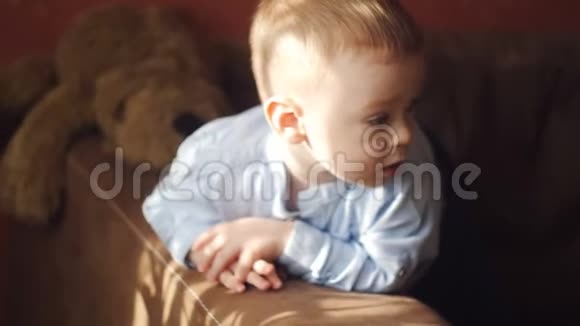 小男孩躺在沙发上环顾四周一缕阳光把婴儿照在沙发上视频的预览图