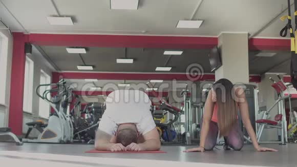 在健身房和女教练单独训练后男人很累一个肥胖的男人和一个女教练视频的预览图