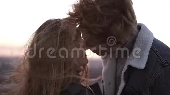 年轻的一对金发碧眼的年轻夫妇在风高的屋顶上站着享受着浪漫的吻视频的预览图