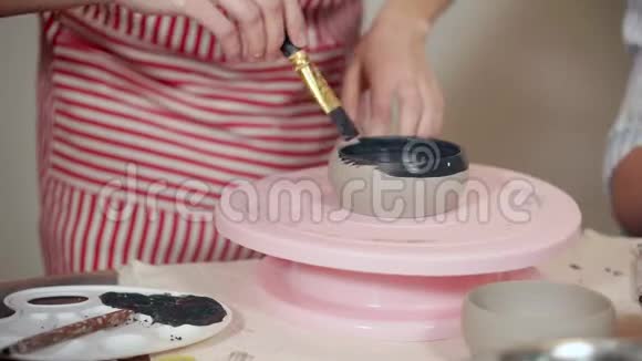 女人正在用陶器旋转支架特写画一个陶瓷杯视频的预览图