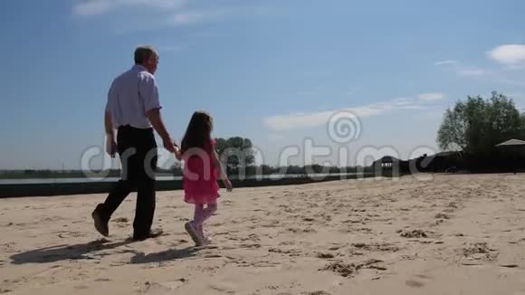 祖父和孙女沿着湖在海滩上散步4K慢慢视频的预览图