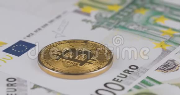 一枚密码货币比特币硬币在100欧元钞票上的4k分辨率特写镜头大镜头旋转成圈视频的预览图