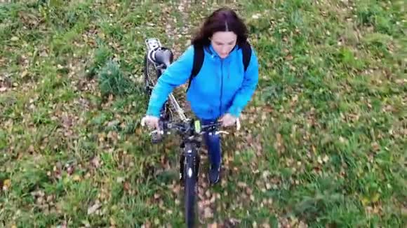 骑着自行车在秋天的公园里散步的女人无忧无虑快乐鼓舞人心的概念视频的预览图