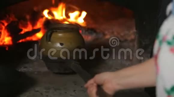 家庭主妇把泥锅放到传统的俄罗斯烤箱里视频的预览图