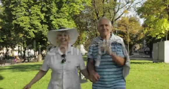 两位高级快乐的游客在市中心公园里跑来跑去视频的预览图