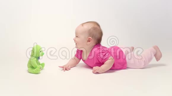 可爱的女婴在白色背景下学习爬行和玩五颜六色的玩具视频的预览图