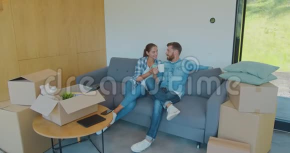 紧张的腰上镜头高兴的笑容白种人夫妻放松和喝茶坐在纸板之间视频的预览图