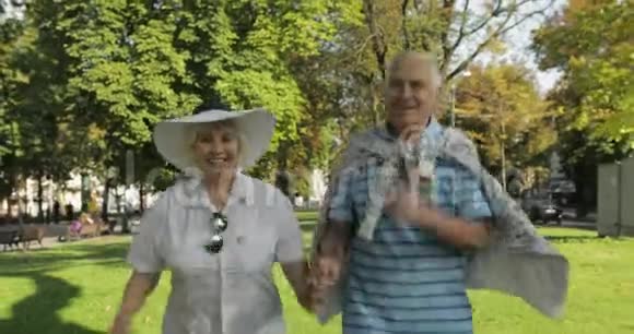 两位高级快乐的游客在市中心公园里跑来跑去视频的预览图