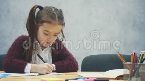 妈妈和女儿坐在灰色背景的桌子旁写作业交流视频的预览图