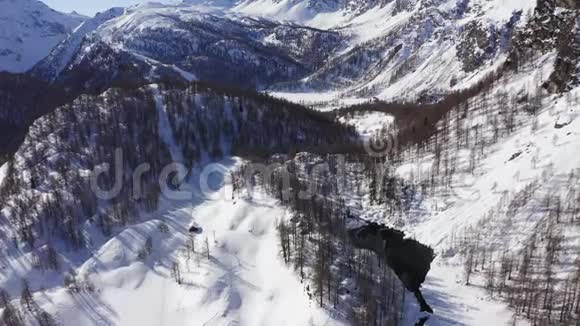 晴朗的冬日空中俯瞰阿尔卑斯湖露出雪山山谷欧洲阿尔卑斯山户外视频的预览图