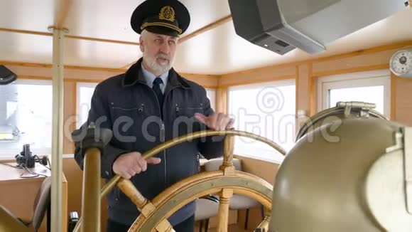 在船长桥上举着方向盘的船长肖像有胡子的水手在航行时转舵视频的预览图