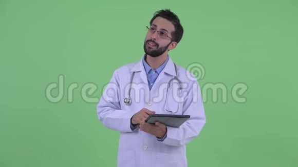 快乐的年轻留胡子的波斯医生在用数码平板电脑思考视频的预览图