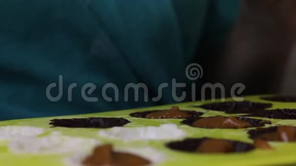 女人为釉面糖果做馅料在硅胶模具里用液态巧克力涂油视频的预览图