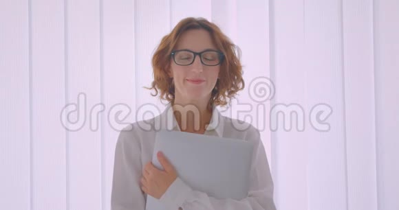 戴眼镜的成年红发白种女商人的特写照片手持笔记本电脑在视频的预览图