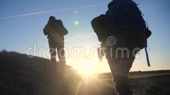 两名游客团队合作背包慢动作行走在夕阳的阳光下走着剪影两个视频的预览图