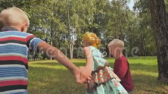 三个快乐的孩子正牵着手在公园里跑步视频的预览图