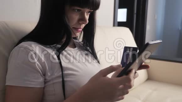 女孩用笔记本电脑数字平板电脑制作网上销售购物概念黑发女人躺在生活沙发上看着商店视频的预览图