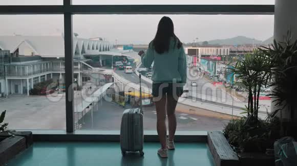 小女孩正在机场窗口附近等待她的航班行李是4k视频的预览图