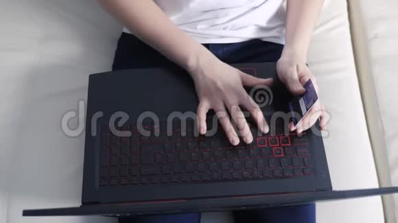 女孩用笔记本电脑数字平板电脑制作网上购物概念黑发女人躺在沙发上看生活视频的预览图