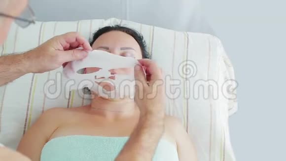 一位男性美容师将保湿面膜应用于水疗中心的女性客户视频的预览图
