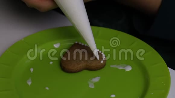 女人把一滴白糖放在姜饼上餐盘附近有带糖霜的饼干视频的预览图