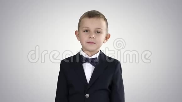 穿着蝴蝶结的小男孩走在渐变背景上视频的预览图