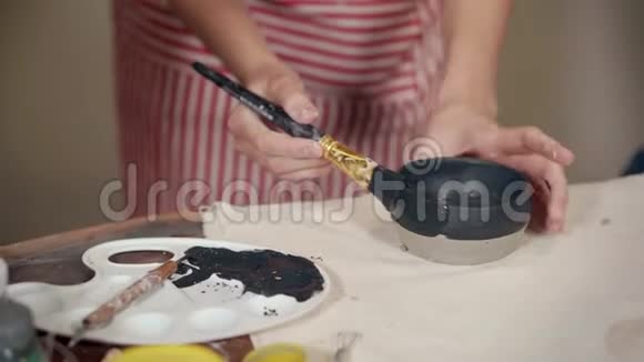陶瓷女孩在陶器工作室用黑漆陶碗着色视频的预览图