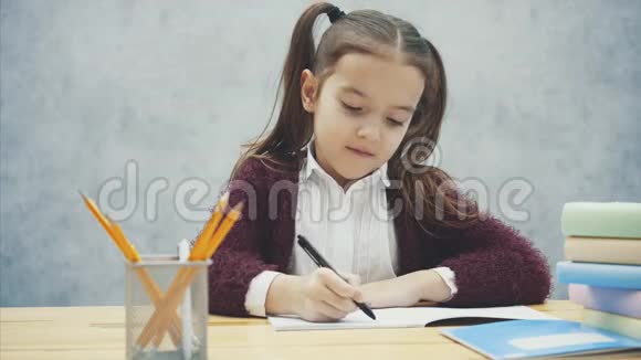 聪明的女学生坐在桌子旁在这期间他写了一个家庭作业数着计算器视频的预览图