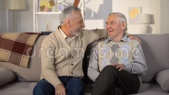 老年男性朋友在家沙发上谈笑风生交谈愉快视频的预览图