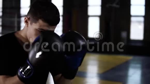 穿着黑色T恤的男子决定拳击手在健身房室内对拳击袋进行打击单独训练战斗机视频的预览图
