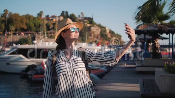 穿着休闲装背包在游艇码头自拍的千禧时髦女游客视频的预览图