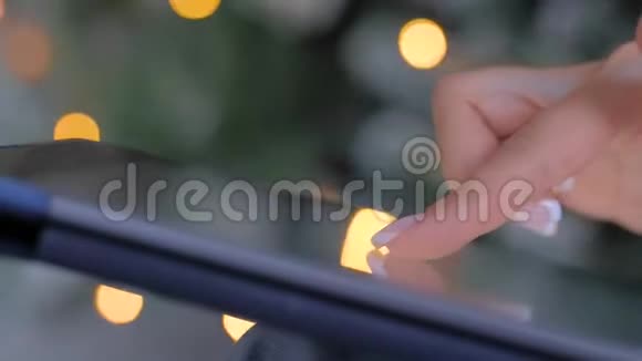 女士使用触摸屏平板电脑圣诞灯背景关闭视频的预览图