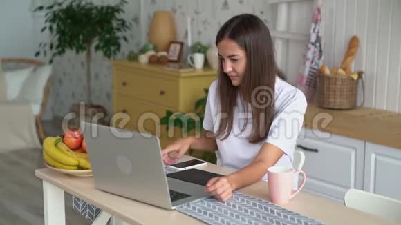 年轻的女人在笔记本电脑上工作带着平板电脑接电话和电话慢动作视频的预览图