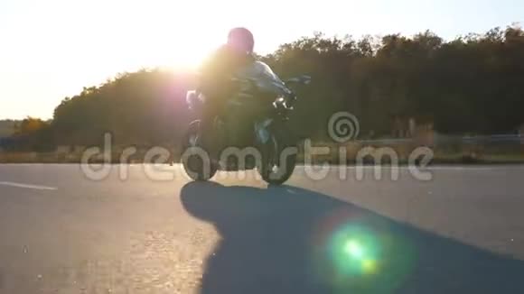 戴头盔的人骑着现代摩托车在高速公路上快速行驶背景是太阳耀斑他的摩托车手视频的预览图