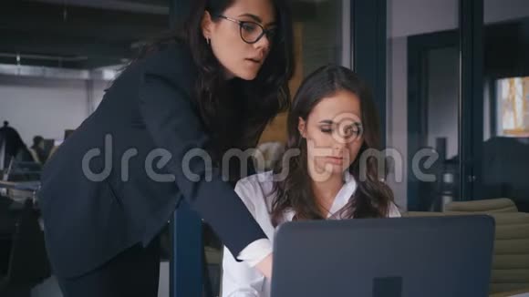 两个女人在讨论一个项目看着办公室里的电脑屏幕两名女商人在工作期间交流视频的预览图