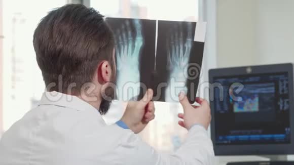 一位男医生在看一位病人的脚x线后视镜头视频的预览图