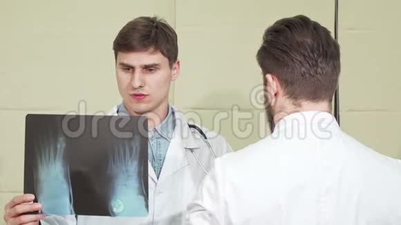 英俊的男医生和他的同事讨论一只脚的x光视频的预览图