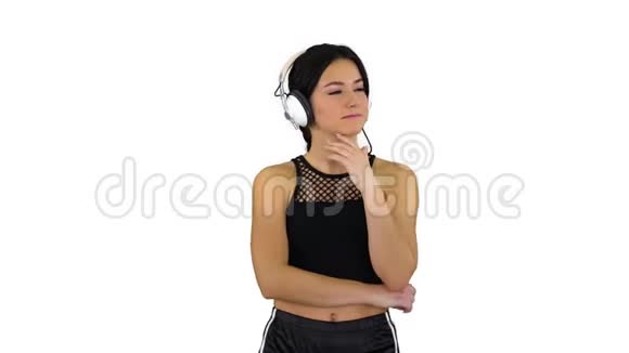 年轻活泼的美女在白色背景下享受耳机里的音乐视频的预览图