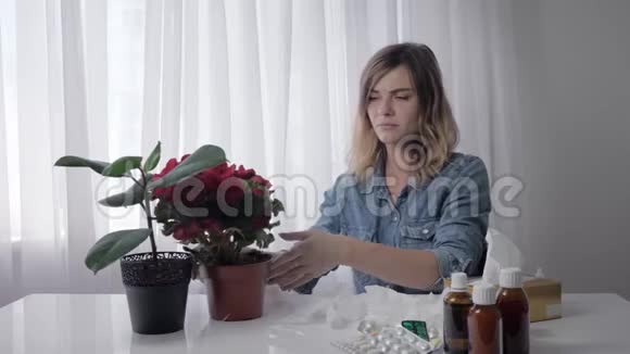 年轻女子打喷嚏一个成年女孩在餐桌上端着药擦鼻子时对花过敏视频的预览图